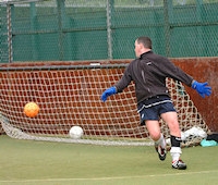 man kicking balls into a net