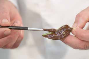 spreading chocolate on a leaf with a paint brush